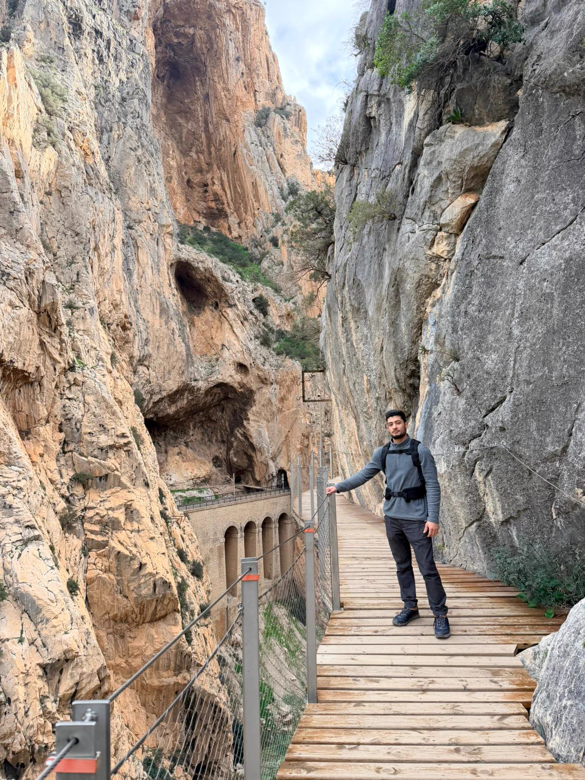 Senderista con casco en una pasarela encajada entre las paredes del Caminito del Rey