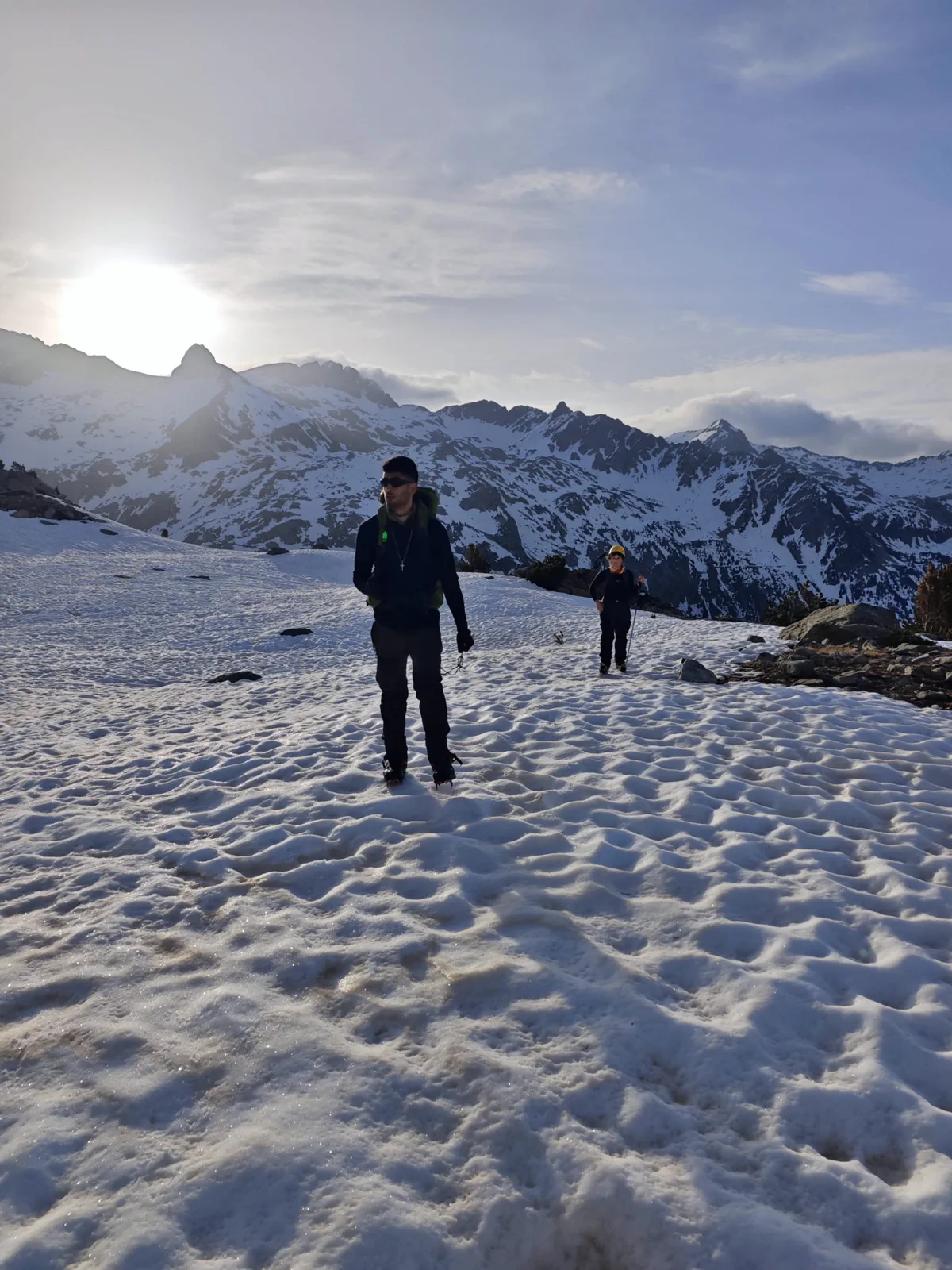 Dos montañeros avanzan por la nieve con las cumbres al fondo