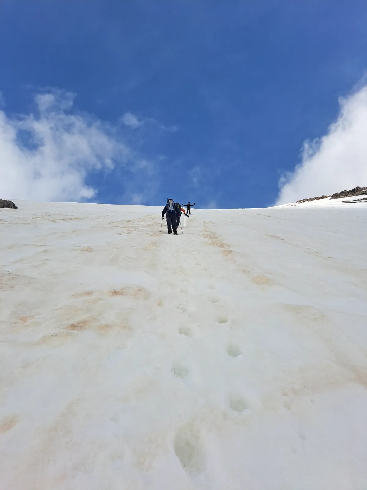 Dos montañeros ascienden por la pendiente superior nevada