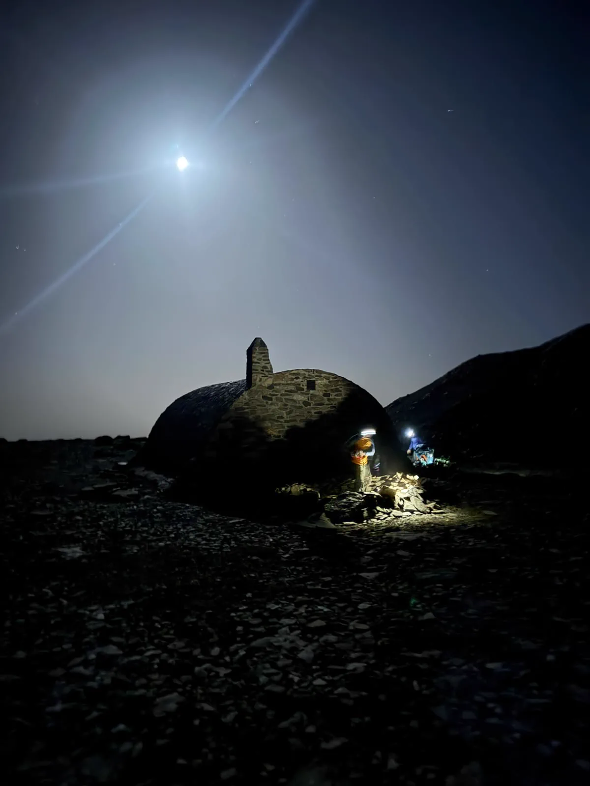 Refugio de piedra iluminado durante una noche de vivac