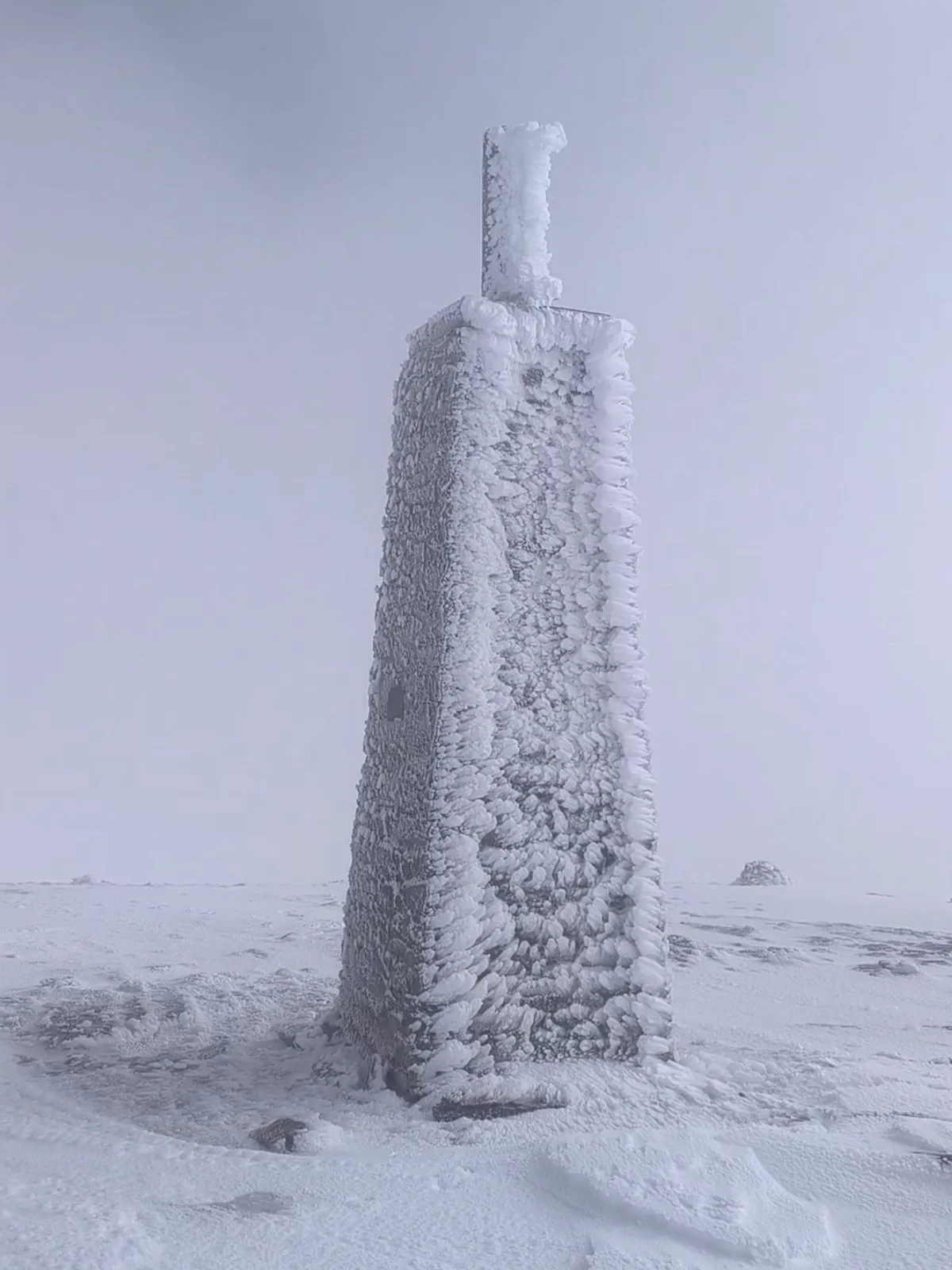 Hito de cumbre cubierto de hielo en La Maroma