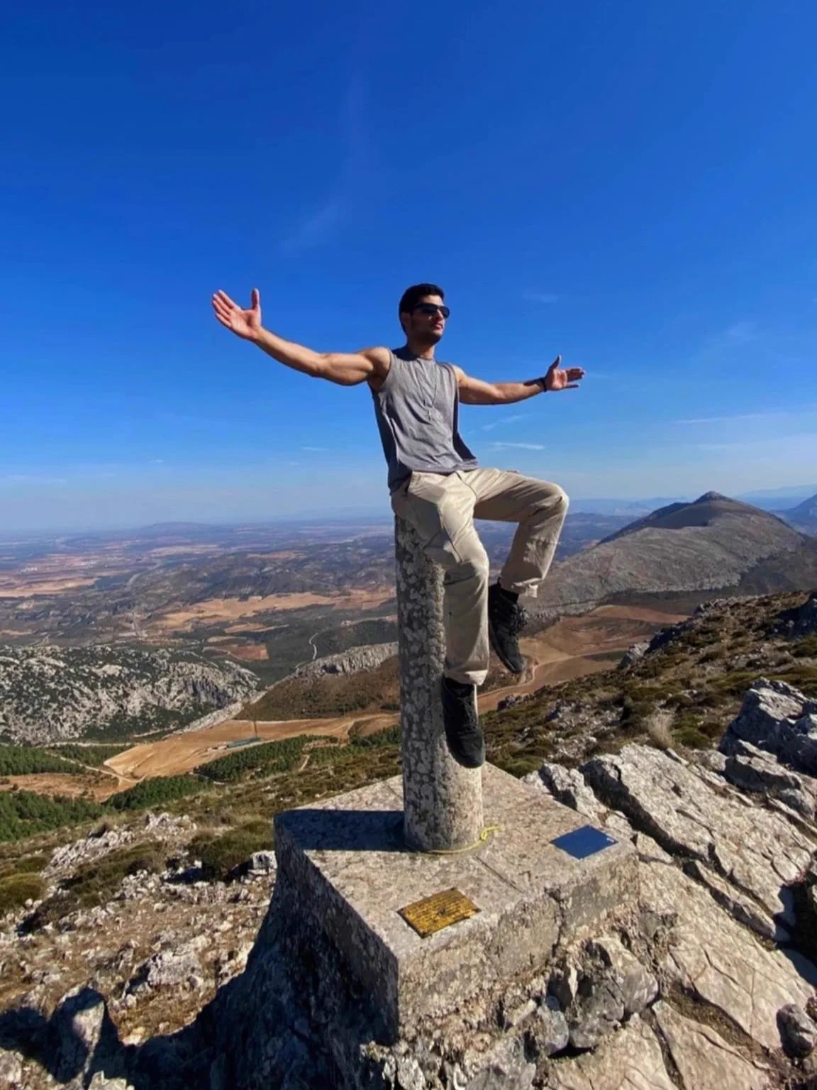 Bauti sobre el vértice geodésico del Pico Huma con el paisaje de Málaga al fondo