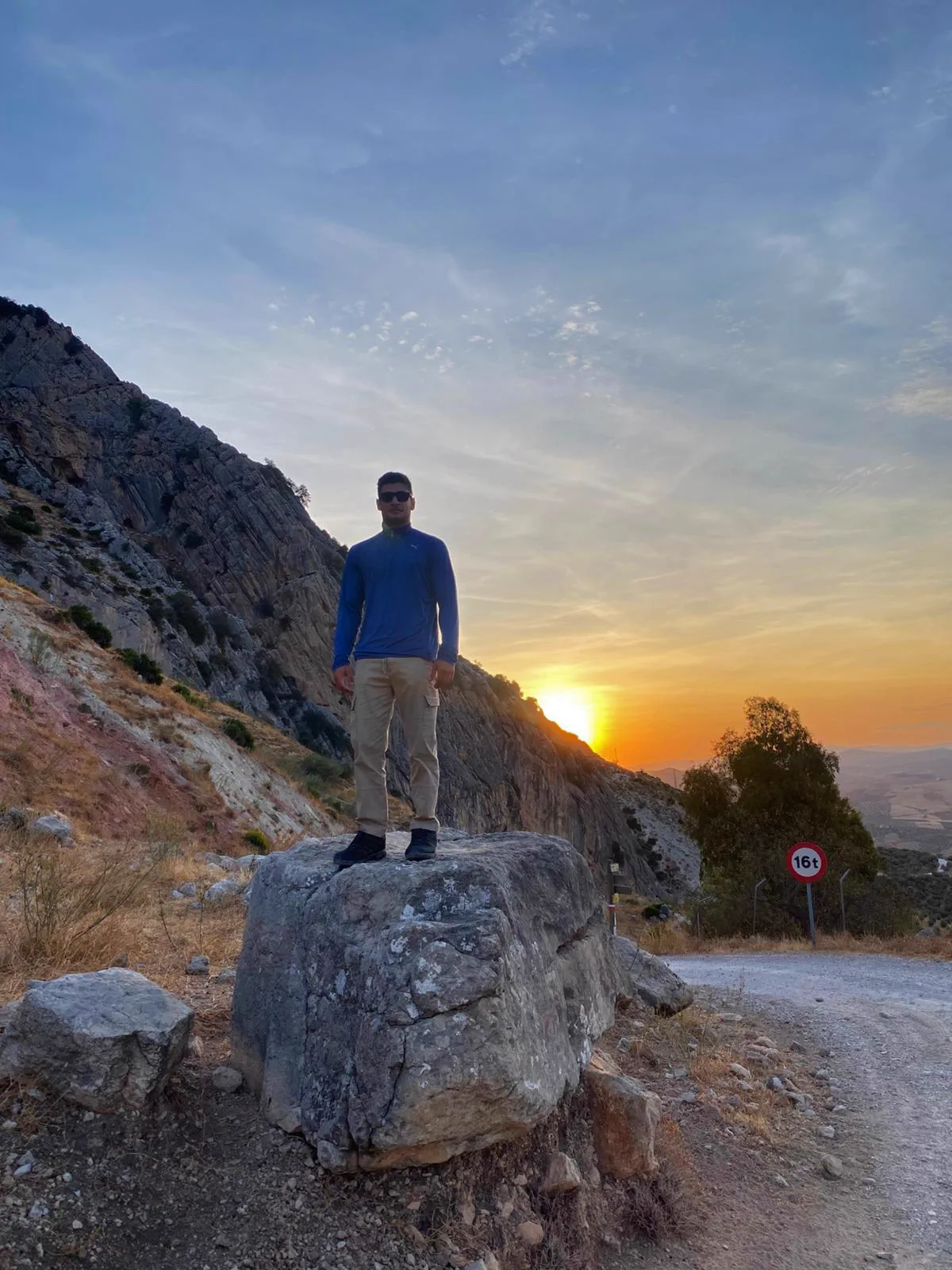 Bauti junto a un bloque de roca al inicio de la ruta con el sol bajo