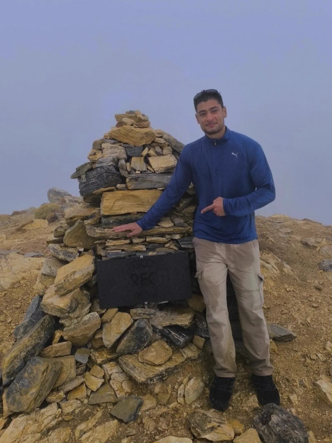 Bauti junto al hito de piedra de la cima del Pico Torrecilla entre la bruma