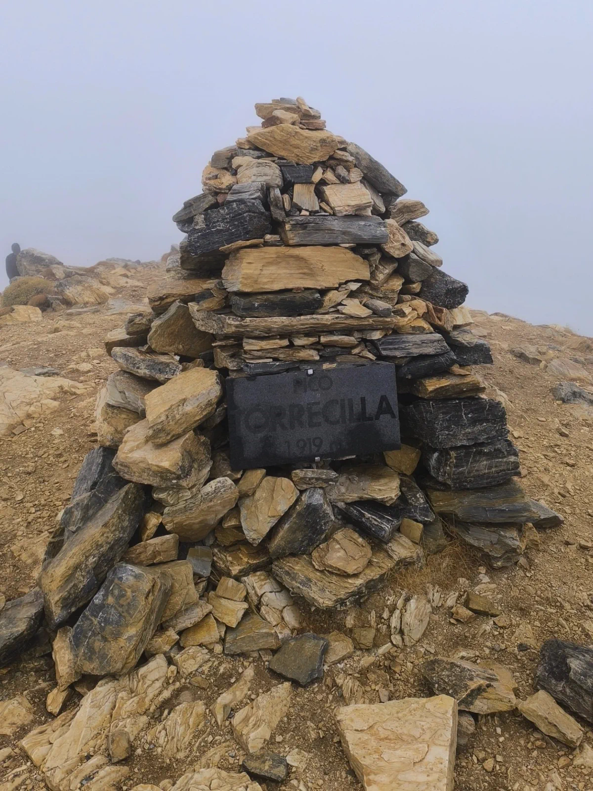 Hito de piedra del Pico Torrecilla rodeado de niebla